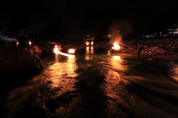 夜の川で火ぶり漁をおこなっている写真