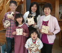 森の時計作りを楽しむ家族の写真