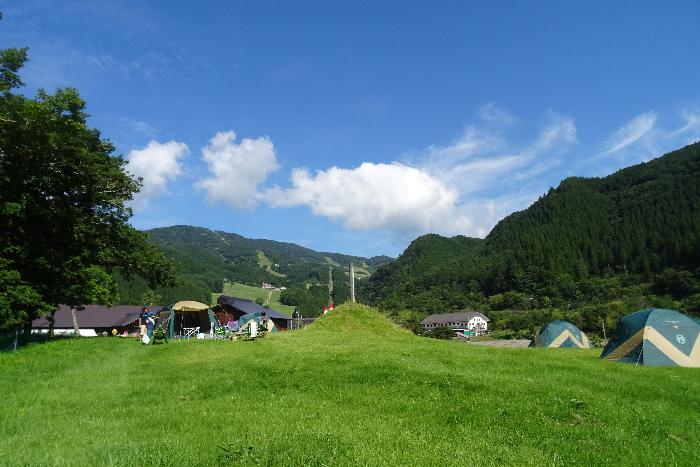 青空の下の高原でキャンプをしている画像