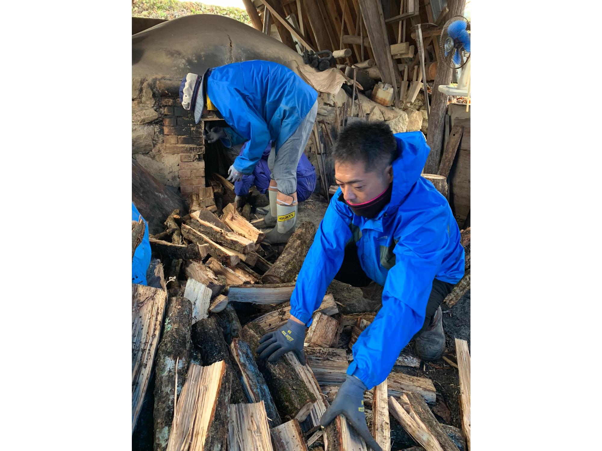 炭焼き窯に薪を詰める作業